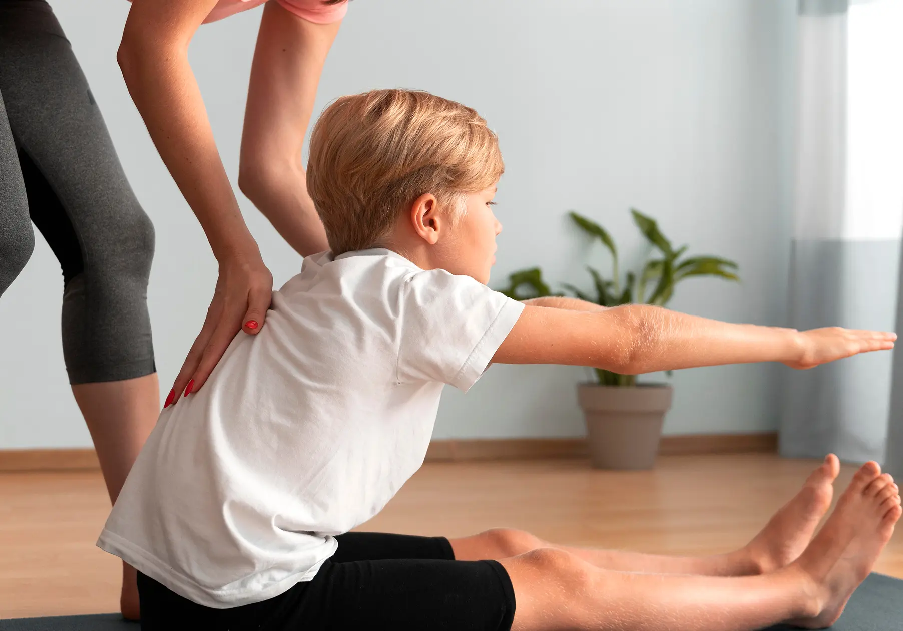 Frau hilft Kind beim Kinderreha