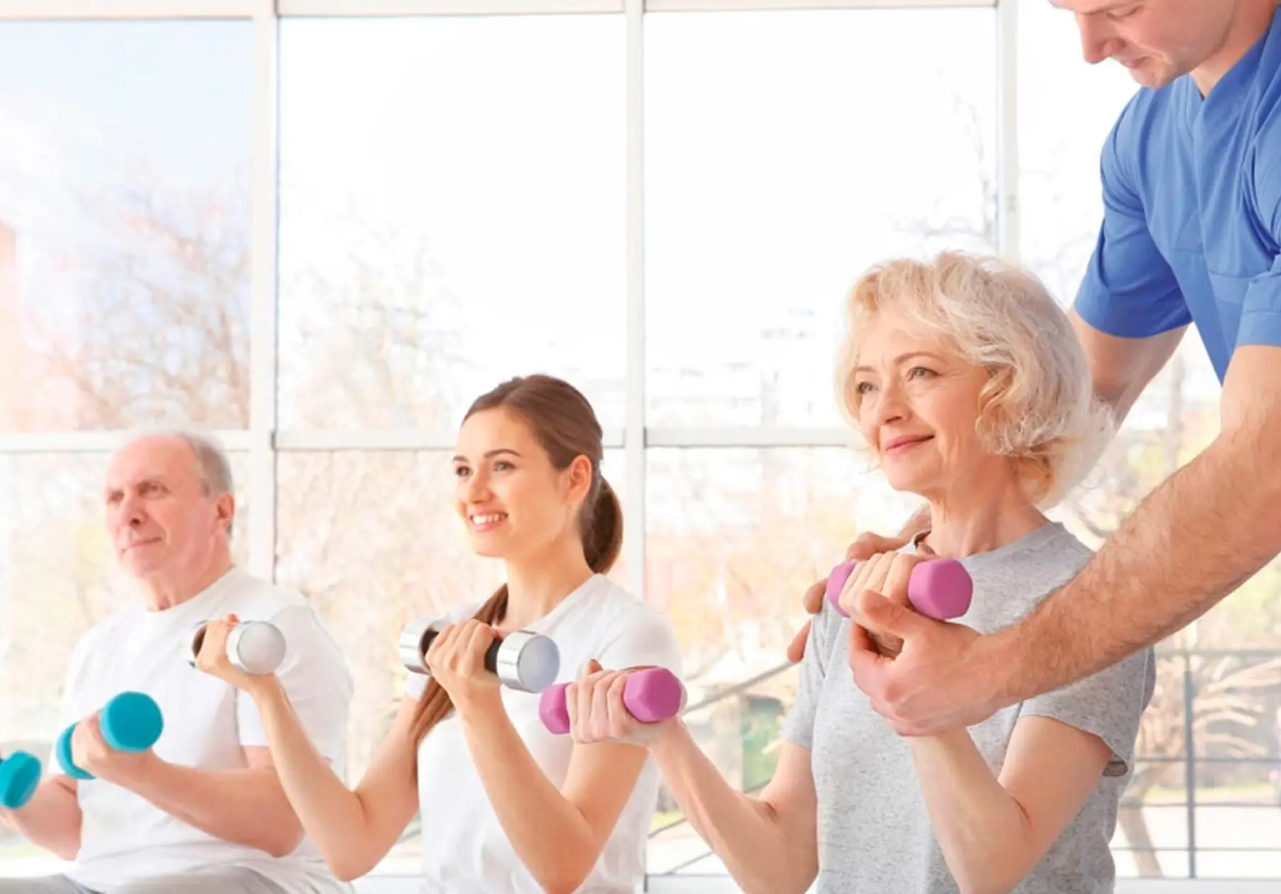 Trainer hilft 3 Personen beim Rehasport