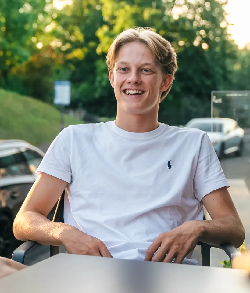 Junge sitzt lachend auf der Terrasse